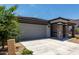 Exterior shot of the home featuring the attached two-car garage, landscaping, and covered entryway at 18021 W Avenida Del Sol --, Surprise, AZ 85387