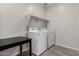 Bright laundry room with white washer and dryer, complemented by a shelf and table at 18021 W Avenida Del Sol --, Surprise, AZ 85387