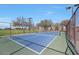 Well-maintained blue tennis court with green borders, surrounded by trees and a chain-link fence, under a clear blue sky at 18021 W Avenida Del Sol --, Surprise, AZ 85387
