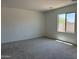 Neutral-toned bedroom with a large window for natural light, carpet floors, and a crisp, clean aesthetic at 18165 W Larkspur Dr, Goodyear, AZ 85338