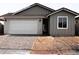 Charming single-story home with gray siding, brick driveway, a white garage door, and well-manicured landscaping at 18165 W Larkspur Dr, Goodyear, AZ 85338