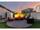 Backyard seating area with stone patio, cushioned seating, brick backdrop, and pleasant nighttime lighting at 21084 E Cherrywood Dr, Queen Creek, AZ 85142
