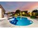 Beautiful backyard pool at dusk with lush landscaping, comfortable seating, and a serene ambiance at 21084 E Cherrywood Dr, Queen Creek, AZ 85142