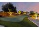 A backyard putting green is surrounded by desert landscape and mature trees with outdoor lighting at 21084 E Cherrywood Dr, Queen Creek, AZ 85142