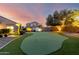 Enjoy a backyard with lush artificial turf, illuminated trees, and a custom putting green for outdoor fun at 21084 E Cherrywood Dr, Queen Creek, AZ 85142