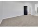 Cozy bedroom with neutral carpet, white walls, and a dark-colored door, offering a simple and inviting space at 22548 W Huntington Dr, Buckeye, AZ 85326