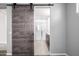 Stylish wood sliding barn door leads to a bright, modern bathroom with a glass-enclosed shower at 24953 N 172Nd Dr, Surprise, AZ 85387