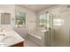Bright bathroom featuring double sinks, a bathtub, and glass-enclosed shower at 2640 N 73Rd Gln, Phoenix, AZ 85035