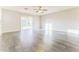 Bright and airy living room with wood-look tile flooring, ceiling fan, and sliding glass door to backyard at 2783 E Mineral Park Rd, San Tan Valley, AZ 85143