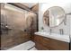 Modern bathroom with sleek vanity, stylish tiling, glass-enclosed shower with wood accents, and round mirror at 3964 S Turquoise Dr, Buckeye, AZ 85326