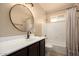 Bathroom with a black vanity, a round mirror, and a shower-tub combination at 4145 W Hayward Ave, Phoenix, AZ 85051
