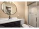 Modern bathroom featuring a vanity with a black cabinet, round mirror, and shower at 4145 W Hayward Ave, Phoenix, AZ 85051
