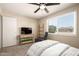 Bright bedroom featuring a ceiling fan, recliner, TV, and large window with natural light at 4145 W Hayward Ave, Phoenix, AZ 85051
