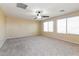 Spacious carpeted bedroom featuring a ceiling fan and bright natural light from the windows at 42564 W Palmyra Ln, Maricopa, AZ 85138