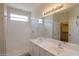 Bathroom featuring double sinks, white tile, walk-in shower, and a large mirror for spacious appeal at 44092 W Stonecreek Rd, Maricopa, AZ 85139
