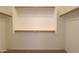 Bright walk-in closet with wood shelving and tan carpeting at 44092 W Stonecreek Rd, Maricopa, AZ 85139