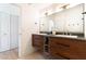 Bright bathroom showcasing a wood vanity, double sinks, and a spacious layout with a view into an open doorway and closet at 5505 E Mclellan Rd # 111, Mesa, AZ 85205