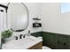 Modern bathroom featuring a round mirror, white countertop, dark fixtures and olive green wainscoting at 6641 N Desert Shadow Ln, Phoenix, AZ 85014