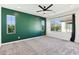 Roomy bedroom features dark green accent wall, neutral carpet, and large bright windows at 6641 N Desert Shadow Ln, Phoenix, AZ 85014