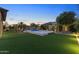 Expansive backyard featuring manicured lawn, lush landscaping, and a sparkling pool with water feature at 6918 E Ivyglen St, Mesa, AZ 85207