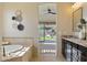 Bright bathroom featuring dual sinks, soaking tub, and a view to the backyard pool area at 6918 E Ivyglen St, Mesa, AZ 85207
