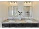 Elegant bathroom vanity showcasing double sinks, granite counters, dark cabinetry, modern mirrors, and decorative floral at 6918 E Ivyglen St, Mesa, AZ 85207