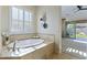 Bathroom showcasing a modern tub with tiled wall decor, and access to the main bedroom at 6918 E Ivyglen St, Mesa, AZ 85207