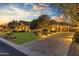 Charming home exterior featuring manicured landscaping, a stone facade, and a brick driveway at twilight at 6918 E Ivyglen St, Mesa, AZ 85207