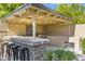 Outdoor kitchen and bar area with stainless steel grill, stone counter, and seating, perfect for entertaining at 6918 E Ivyglen St, Mesa, AZ 85207