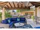 Covered patio with a stylish seating area, outdoor kitchen, and a TV, creating an ideal space for relaxation and entertainment at 6918 E Ivyglen St, Mesa, AZ 85207
