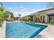 An impressive backyard pool, surrounded by lush greenery and palm trees, next to an outdoor kitchen at 6918 E Ivyglen St, Mesa, AZ 85207