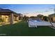Tranquil backyard oasis featuring a sparkling pool with a waterfall and lush green lawn at dusk at 6918 E Ivyglen St, Mesa, AZ 85207