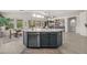 Modern kitchen island with stainless steel dishwasher, sink, and cabinetry overlooking the living area at 7701 E Portobello Ave, Mesa, AZ 85212