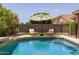 Backyard swimming pool area featuring lounge chairs and large umbrella at 7701 E Portobello Ave, Mesa, AZ 85212