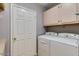 Laundry room with a white washer and dryer and plenty of storage cabinets at 8245 E Bell Rd # 103, Scottsdale, AZ 85260