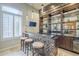 Stylish bar area with custom cabinetry, decorative lighting, and seating for entertainment at 8248 E Arroyo Hondo Rd, Scottsdale, AZ 85266