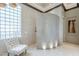 Elegant bathroom featuring a textured wall, unique glass-block window, and stylish chair at 8248 E Arroyo Hondo Rd, Scottsdale, AZ 85266