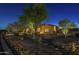 Inviting home exterior at night with mature trees, desert landscaping, and pathway lighting at 8248 E Arroyo Hondo Rd, Scottsdale, AZ 85266