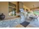 Covered patio featuring stone accent walls, an outdoor kitchen area with a stainless steel grill and dining table at 8248 E Arroyo Hondo Rd, Scottsdale, AZ 85266