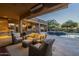 Covered patio with comfortable seating, dining area, outdoor kitchen, and a view of the pool and backyard at 8248 E Arroyo Hondo Rd, Scottsdale, AZ 85266
