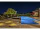 Stunning backyard pool and spa illuminated at night, surrounded by lush landscaping and lounge areas at 8248 E Arroyo Hondo Rd, Scottsdale, AZ 85266