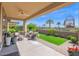 Relaxing covered patio, with lounge seating, a green lawn, and manicured landscaping for outdoor enjoyment at 93 E Santa Lucia Ln, Queen Creek, AZ 85140