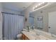 Well-lit bathroom featuring a sink, toilet, and a shower with a blue curtain at 17434 N 46Th Pl, Phoenix, AZ 85032