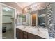 Bathroom featuring double sinks, mosaic tile, and an adjoining walk-in closet offering ample storage at 10228 E Carol Ave, Mesa, AZ 85208