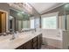 Bathroom featuring double sinks, mosaic tile accents, and a separate tub and shower for a luxurious experience at 10228 E Carol Ave, Mesa, AZ 85208