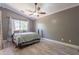 Inviting bedroom with ceiling fan, large window, and wood floors, creating a relaxing and stylish space at 10228 E Carol Ave, Mesa, AZ 85208