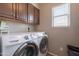 Bright laundry room features a Samsung washer and dryer, cabinets, and a window at 10228 E Carol Ave, Mesa, AZ 85208