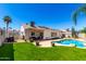 Backyard with a sparkling pool, lush lawn, covered patio, and privacy fencing at 1042 E Utopia Rd, Phoenix, AZ 85024