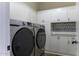 Modern laundry room with front-loading washer and dryer, white cabinets, and stylish tile accents at 1123 E Shepherds Way, Casa Grande, AZ 85122