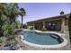 Swimming pool surrounded by palm trees, with a covered patio and outdoor kitchen area in the background at 1123 E Shepherds Way, Casa Grande, AZ 85122